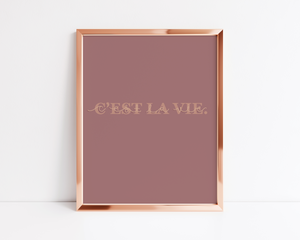 Open image in slideshow, A print in a rose gold frame with a dark blush background and the phrase &quot;C&#39;EST LA VIE&quot; in serif block letters with cursive overlay 
